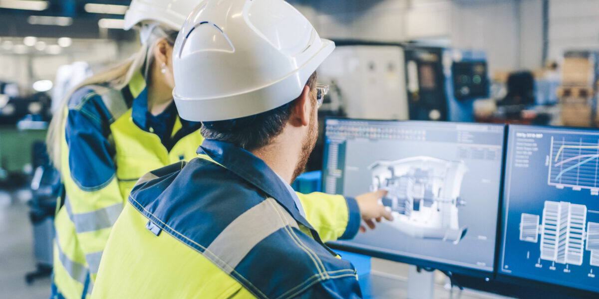 At the Factory: Male Mechanical Engineer and Female Chief Engineer Work Together on the Personal Computer, They Discuss Details of the 3D Engine Model Design.